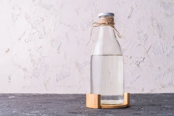 Стеклянная бутылка с абсолютно чистой дистиллированной водой, изолированной на поверхности гранжа — стоковое фото