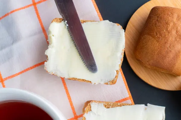 Osoba dát kus másla na plátek chleba a šálek kávy na stůl, snídaně vaření — Stock fotografie