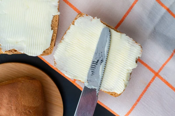 Osoba dát kus másla na plátek chleba a šálek kávy na stůl, snídaně vaření — Stock fotografie