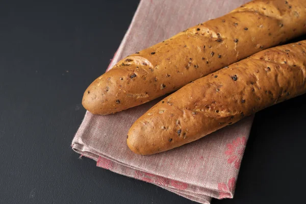 Čerstvý chutný chléb nebo bageta na černém povrchu v kuchyni — Stock fotografie