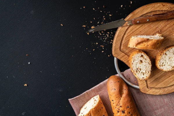 Čerstvý chutný chléb nebo bageta na černém povrchu v kuchyni — Stock fotografie