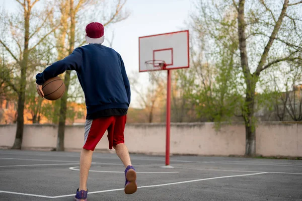 Ung basketballspiller som kan drible utendørs på asfaltbanen i sommersesongen – stockfoto