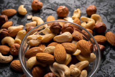 Karanlık bir masada, sağlıklı ve organik gıda kavramlarının olduğu bir kasede farklı ham kokteyl fındıkları karıştırdım.