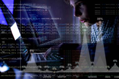 Dizüstü bilgisayarın önündeki genç programcı gece vakti bir kod yaz