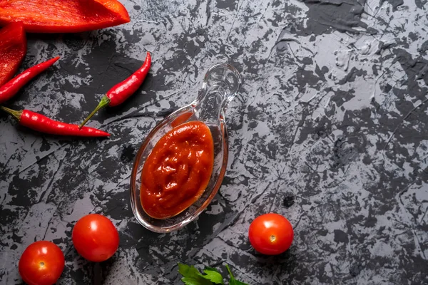 Dom gotowane sos pomidorowy lub ketchup w szklanym kubku, pikantne jedzenie pieprz na stole w kuchni — Zdjęcie stockowe