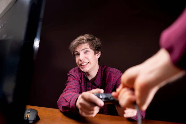 Осторожные родители зависимого от видеоигр молодого человека отбирают у него джойстик b — стоковое фото