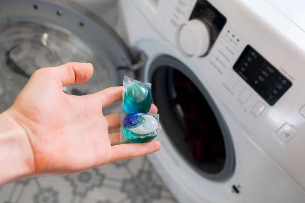 Лица руки положить специальный стручок или капсулу в стиральную машину с грязной тканью — стоковое фото