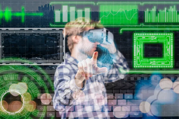 Junger Mann in virtueller Brille, der mit Grafiken arbeitet, Hologramm ihn umgibt, futuristisches Gerätekonzept b Stockbild