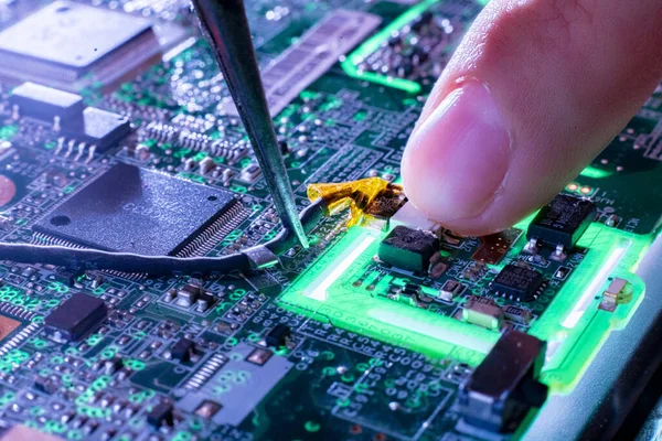 Närbild reparatörer finger på den gröna elektriska kretskortet d — Stockfoto