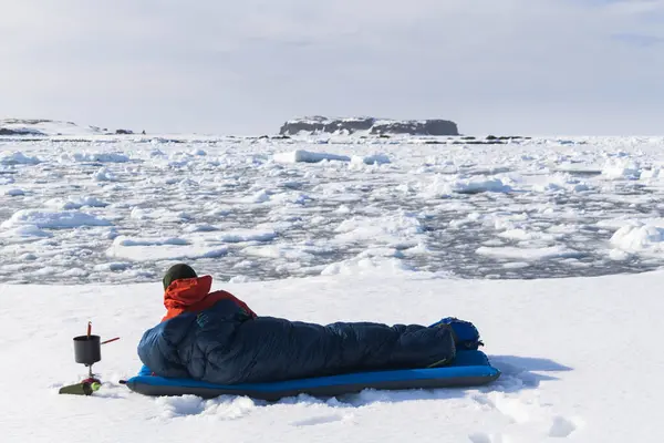 男子徒步旅行者躺在雪地上的睡袋里 — 图库照片