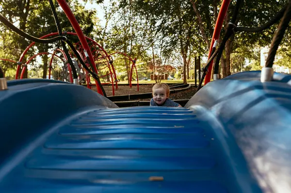 Mały Chłopiec Wspinaczka Niebieski Zjeżdżalnia Parku — Zdjęcie stockowe