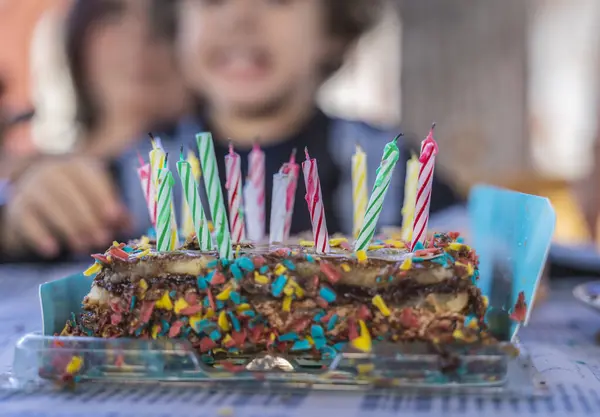 チョコレートの誕生日ケーキの2階 キャンドルがたくさんある 背景には認識できない子供 — ストック写真