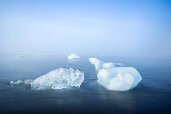 アイスランドの霧深い朝にジョクルサロン氷河ラグーン近くのダイヤモンドビーチで海によって洗浄された氷の塊 — ストック写真