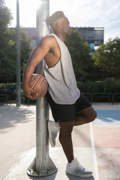 Чорний Чоловік Баскетбольним Ячем Спирається Полюс Відпочиває Спортивному Майданчику Місті — стокове фото