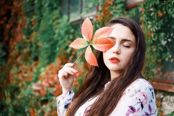 一个漂亮的女孩 她的脸旁边拿着一片野葡萄 — 图库照片