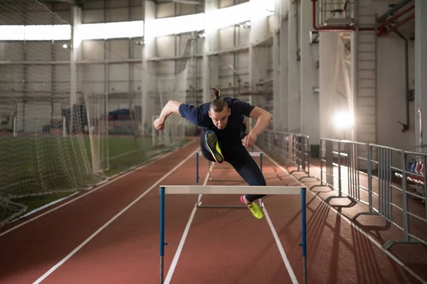 陸上競技中の努力で障害物を飛び越える強い男性選手 — ストック写真