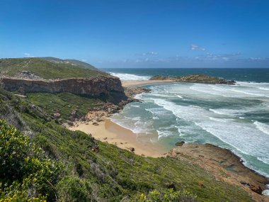 Hint Okyanusu manzarası ve Robberg Doğa Rezervi, Plettenberg Körfezi sahilleri, Güney Afrika mavi gökyüzüne karşı