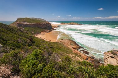 Hint Okyanusu manzarası ve kıyı şeridi Robberg Doğa Rezervi 'nde ahşap patika, Plettenberg Körfezi, Güney Afrika mavi gökyüzüne karşı