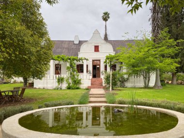 De Kombuy Estate, Cangoo Valley, Oudtshoorn, Güney Afrika 'daki Cape Dutch mimari tarzında tarihi bina bulutlu gökyüzüne karşı