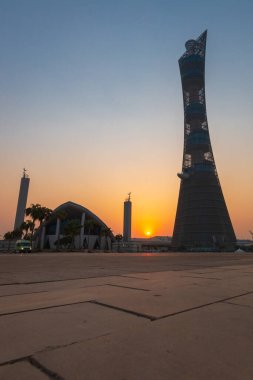 Doha, Qatar  October 1, 2019: The Torch Tower in Doha Sport City Complex at sunset next to Aspire Masjid Mosque against clear sky.