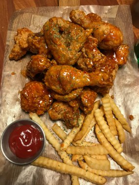 Acı soslu kızarmış tavuk. Kağıt üzerinde patates kızartması.