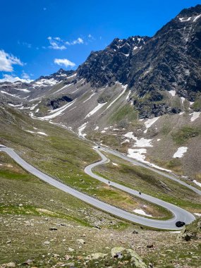 Avusturya 'daki Oetztal' a bakan Timmelsjoch viraj yolunda yüksek alp dönüşleri; geç kar yamaları ve mavi gökyüzü ile kayalık yamaçlar
