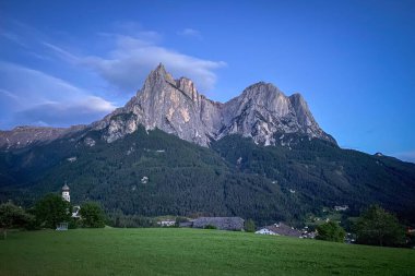 Schlern 'in (başkent) manzarası. Seis 'in üstünde. Siusi) Güney Tyrol 'da, St. Valentin Kilisesi' nin solunda; mavi gökyüzü altında kireçtaşı zirveleri ve çayırların üzerinde