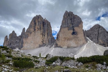 İtalya 'daki Tre Cime di Lavaredo' nun yakın görüntüsü, soluk kireç taşı parkeleri üzerinde yükselen üç Dolomite kulesi ve mavi gökyüzüne karşı mavi bulutlar.
