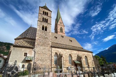 Terlan 'daki Parish Kilisesi (Terlano), Güney Tyrol, Itayl; Romanesk Kulesi, Gotik Kule ve mezarlığın üstündeki çatı desenli, mavi gökyüzü altında bulutlu alp zemin