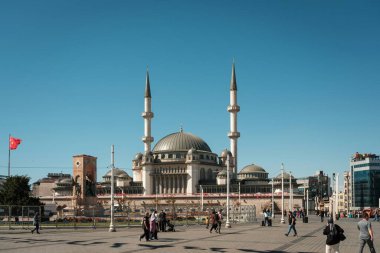 İstanbul, Türkiye - 6 Ekim 2025: Taksim Camii 'nin ikiz minareleri soldaki Cumhuriyet Anıtı ve açık mavi gökyüzü altında yayalar görülüyor