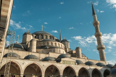 İstanbul, Türkiye 'de Sultanahmet Camii' nin (Mavi Cami) çağlayan kubbeleri, yükselen minareleri ve mavi gökyüzünün altında yükselen avlu kemerleriyle alçak açılı görüntüsü