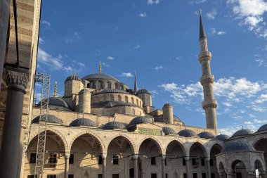 İstanbul, Türkiye 'de Sultanahmet Camii' nin (Mavi Cami) çağlayan kubbeleri, yükselen minareleri ve mavi gökyüzünün altında yükselen avlu kemerleriyle alçak açılı görüntüsü