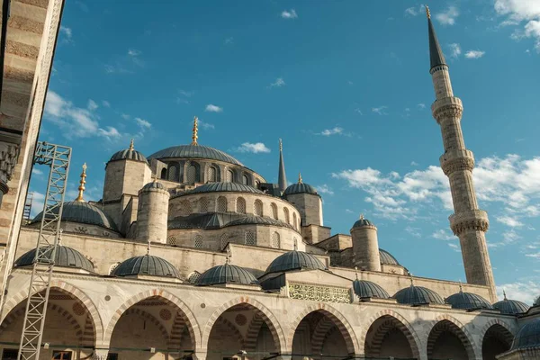 İstanbul, Türkiye 'de Sultanahmet Camii' nin (Mavi Cami) çağlayan kubbeleri, yükselen minareleri ve mavi gökyüzünün altında yükselen avlu kemerleriyle alçak açılı görüntüsü