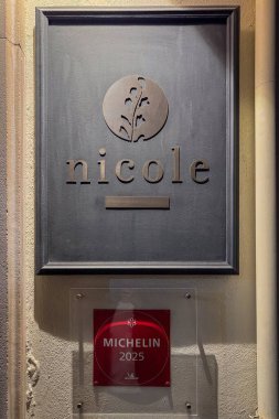 İstanbul, Türkiye - 7 Ekim 2026: Nicole Restoran tabelasının duvarında Michelin 2025 plaketi ve bir yıldız ödülü asılı, geceleri ılık ışık ve desenli taş yüzeyli