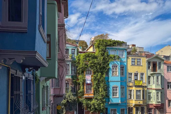 İstanbul, Türkiye - 8 Ekim 2025: Balat ön cephesinde gür sarmaşıklı renkli tarihi evler bulutlu mavi gökyüzüne karşı