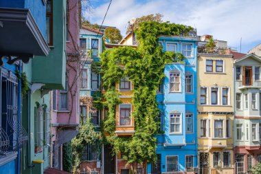 Türkiye, İstanbul 'da bulutlu mavi gökyüzüne karşı Balat cephesinde bereketli sarmaşıklı renkli tarihi evler