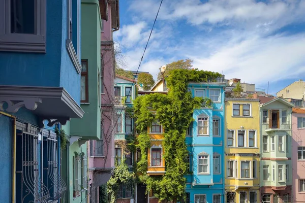 Türkiye, İstanbul 'da bulutlu mavi gökyüzüne karşı Balat cephesinde bereketli sarmaşıklı renkli tarihi evler