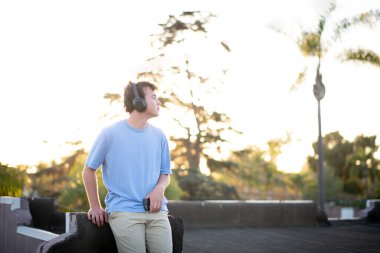 Güneş ışığına karşı kulaklıklı genç adam.