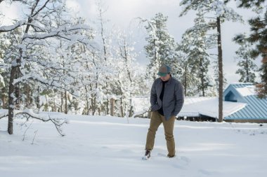 Şapkalı adam kış mevsiminde dışarıda poz veriyor.