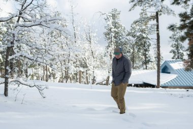 Şapkalı adam kış mevsiminde dışarıda poz veriyor.