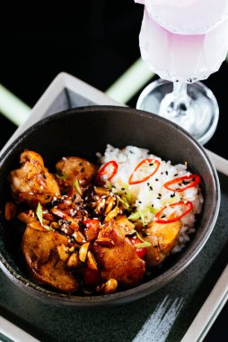 Siyah arka planda pirinç bulunan Asya usulü tavuk kanatları.