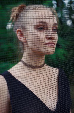 Genç bir kadının yüzü, ormandaki koruyucu bir ağ ile çevrilidir.