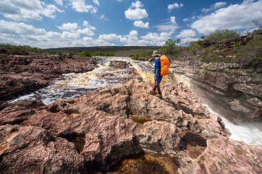 Kayalık nehir manzarasında güzel bir şelalede sırt çantası.