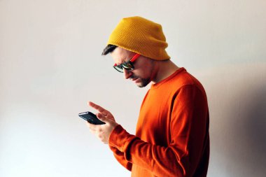 Young man dressed in orange looking his phone.