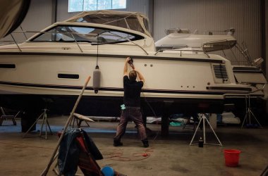 Marine technician engineer polishing a yacht boat in a warehouse