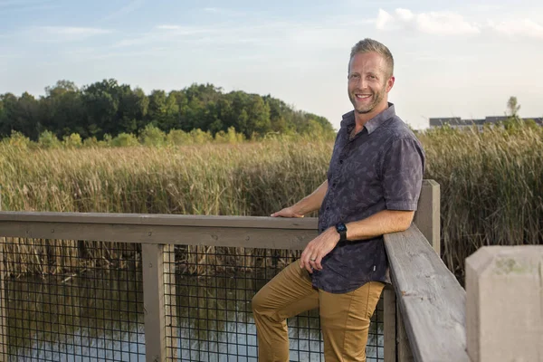 Een Knappe Glimlachende Man Leunt Tegen Een Leuning Een Wetlands — Stockfoto