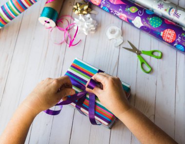 Beyaz ahşap bir arka planda elinde Noel süslemeleri tutan kadın elleri