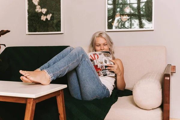 Young Blonde Woman Read Magazine Sofa — стокове фото