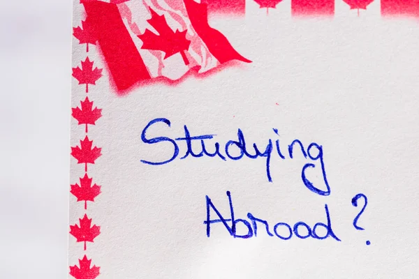 Studying abroad handwriting on paper with Canada flag. Writing text on memo post reminder. Bucharest, Romania, 2020.