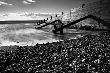 Denizdeki bir rıhtımın siyah beyaz fotoğrafı.